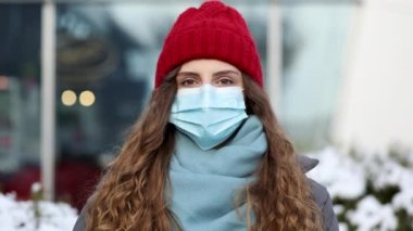 Salgın koronavirüs covid konsepti. Corona virüsü ikinci salgını önlemek için cerrahi koruyucu maskeli kıvırcık esmer kadın. Yüzünde koruyucu maske olan kız. 4K