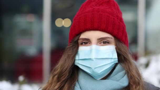 Portrait of Caucasian young curly female in medical face mask standing on winter street. Crowd people sick covid-19. Epidemic coronavirus. Pandemic flu corona virus — Stock Video