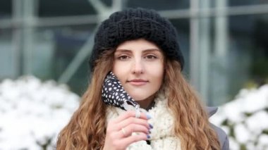 Coman tıbbi maskeyi çıkarıyor. Kadın derin derin nefes alıyor ve arka plandaki kameraya gülümsüyor. Sağlık ve tıbbi konsept. Kış sokağında duran kıvırcık kadın portresi.