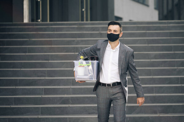 Fired man walking outdoor. Depressed jobless person. Unemployment concept. Left without money. Sad male office worker in depression with box of personal stuff. Businessman lost job.
