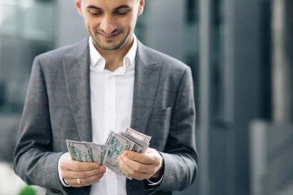 Knappe rijke man dragen stijlvolle pak tellen geld staande in de straat in de buurt van kantoorgebouw — Stockfoto