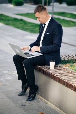 Mesafe çalışıyor. Takım elbiseli izole bir adam. Yakışıklı genç iş adamı dışarıda oturup laptopuyla çalışıyor. 2020 Krizi. Coronavirüs salgını