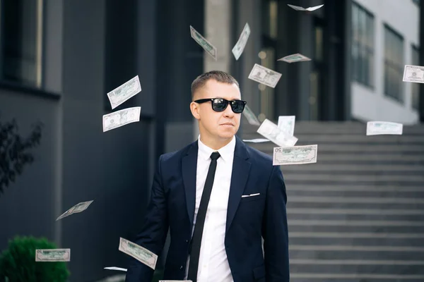 Pluie d'argent, chute de dollars. portrait photo de joyeux riche beau homme d'affaires dans des lunettes et costume jette de l'argent. heureux beau homme jetant des dollars — Photo