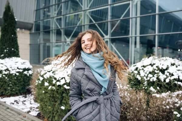 Charming young curly woman with a magnificent brown hair, big brown eyes and stylish look turns to camera and smiles. Attractive young lady is rushing in the winter city-center — Stock Photo, Image