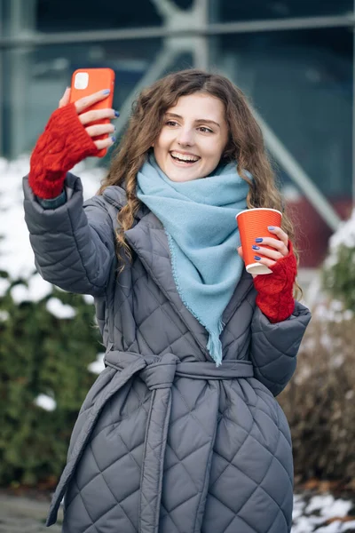Vrouwelijke blogger maakt video 's voor haar sociale pagina op straat in de winter. Vakantie winter buiten krullend meisje. Online zijn, sociale netwerken — Stockfoto