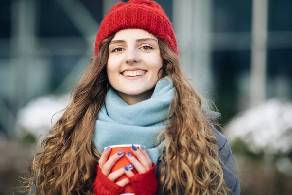 Wesoły wspaniały kręcone brunetka w modzie zimowej trzymając filiżankę kawy na tle miejskim. Koncepcja szczęścia, ferie zimowe, Boże Narodzenie, napoje i ludzie. Kręcone samice stojące na zimowej ulicy — Zdjęcie stockowe