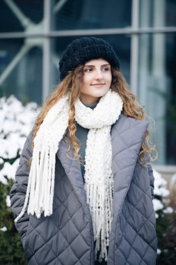 Muhteşem kıvırcık saçlı kadın modern şehir manzarasının ortasında dururken büyüleyici bir şekilde gülümsüyor. Mutlu Genç Kadın Hayattan Hoşlanıyor