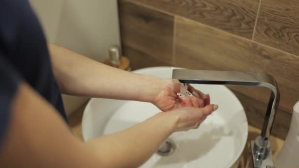 Las manos de la mujer se lavan las manos en un lavabo para lavar la piel y el agua fluye a través de las manos. Concepto de salud, limpieza y prevención de gérmenes y coronavirus en contacto con las manos. — Vídeo de stock