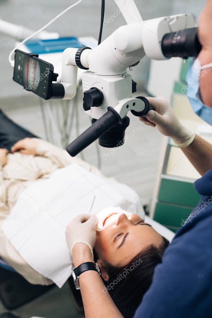 Close-up of a dentist using microscope. Modern equipment microscope in dental office. Doctor dentist using dental microscope in modern dental office. The endodontist is treating canals
