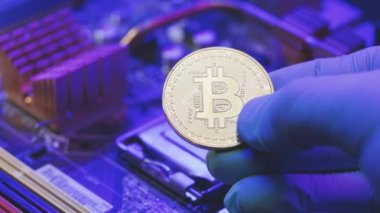 İş adamlarının yakın çekimleri, anakart arka planında altın Bitcoin 'i tutuyor. Parmaklarda kripto para. İnsan gelecekteki para birimini gösteriyor. Madencilik, ticaret