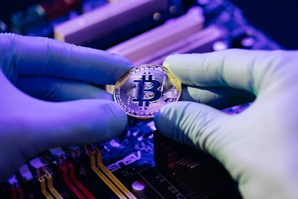 İş adamlarının yakın çekimleri, anakart arka planında altın Bitcoin 'i tutuyor. Parmaklarda kripto para. İnsan gelecekteki para birimini gösteriyor. Madencilik, ticaret