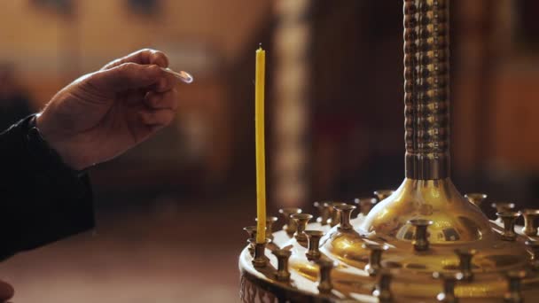 Close-up singola fiamma della candela isolato sullo sfondo della Chiesa. Mano uomo accende piccola candela in chiesa. Portacandele con candele singole nella Chiesa. tema delle tradizioni e dei rituali cristiani ortodossi — Video Stock