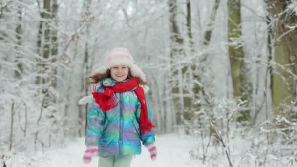 Lustiges lachendes Kindermädchen, das in einem schönen verschneiten Park läuft. Glückliches Mädchen beim Winterspaziergang in der Natur. Positivität ausdrücken, echte helle Emotionen, Lächeln — Stockvideo