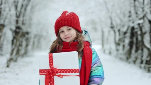Entzückendes kleines Mädchen mit Weihnachtsgeschenk im Winter im Freien. Kleines Mädchen hält Geschenkbox an Weihnachten in der Hand — Stockvideo
