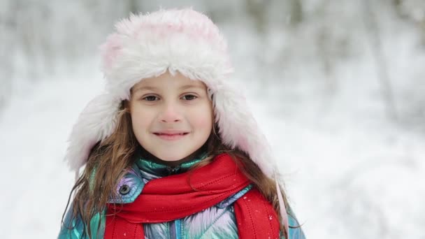 Kar içinde pembe şapkalı küçük bir kız portresi. Soğuk kış gününde, açık havada, sıcacık şapkalı şirin bir kız. Güzel çocuk kışın tadını çıkarıyor. — Stok video