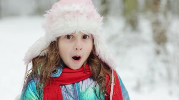 Porträt eines fröhlichen kaukasischen kleinen netten Mädchens mit überraschtem, glücklichem Gesicht. Kleines Mädchen im Gesicht überraschte Kind, das Spaß am Wintertag hatte. Konzept für Feiertage und Feiern — Stockvideo