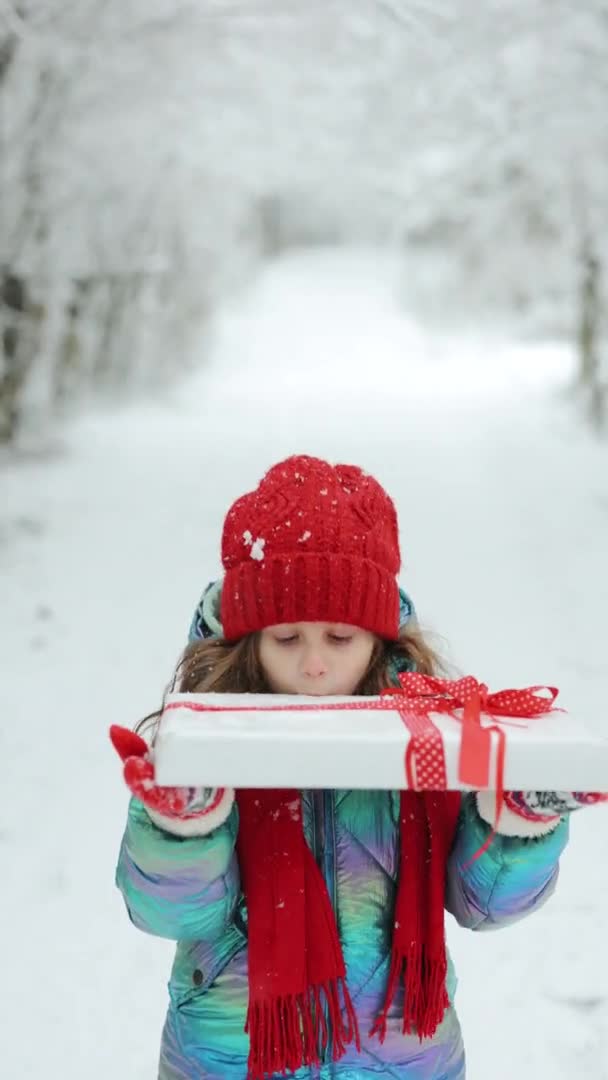 一个6-7岁的可爱女孩手里拿着节日礼物过生日礼物的垂直视频。圣诞当天快乐女孩从礼品盒里偷窥的画像 — 图库视频影像