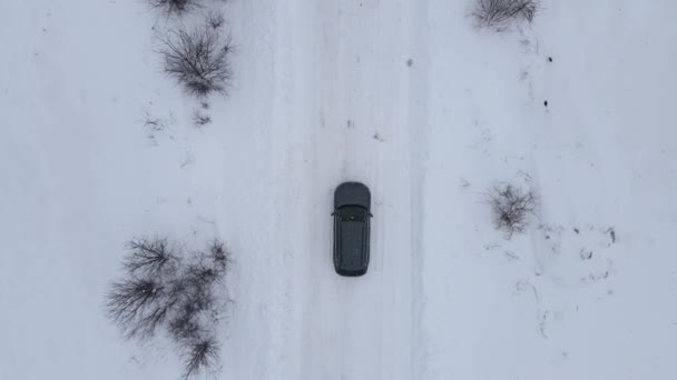 Karla kaplı bir yolda giden hava manzaralı araba. Karlı, buzlu dağ yolunun manzarası. Kışın tehlikeli yolculuk durumu — Stok video