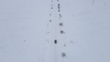 Hava manzaralı araba kaygan karla kaplı bir yolda ilerliyor. Bir arabanın üzerinden uçuyor. Kar fırtınası tüm araziyi kaplıyor.