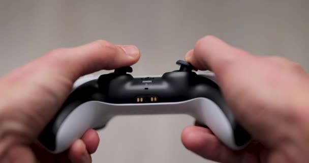 Lviv, Ucrania - 26 de febrero de 2021: el jugador tiene el control de la nueva consola de juegos PlayStation 5. Hombre presiona botones en el juego de joystick y jugar juego. Controlador Dualsense — Vídeo de stock