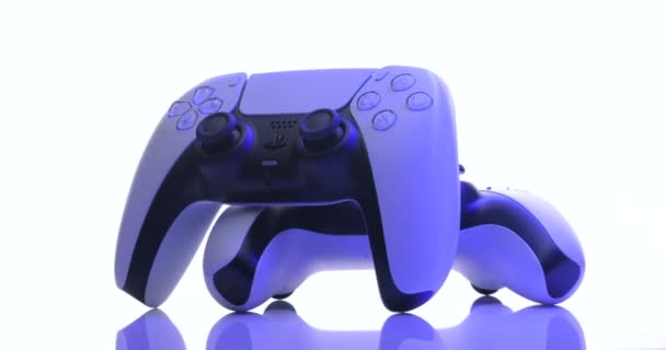 Lviv, Ucraina - 27 febbraio 2021: Due joystick della console TV Sony PlayStation 5 girano su sfondo bianco. Vista ravvicinata di 2 controller dalla nuova console con luce blu — Video Stock