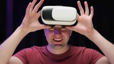 Sanal gerçeklik kulaklığı takan gülümseyen genç adam evdeki kanepede oturuyor. VR gözlükleri sosyal ağ robotu. Eğlenceli oyundu. Artırılmış Gerçeklik