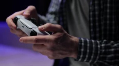 Erkeklerin elleri joystick 'i tutuyor, video oyunu oynuyor ve eğleniyor. Beyaz bir joystick tutan adamın yakın plan görüntüsü yan konsol ve TV 'de bir video oyunu oynuyor.