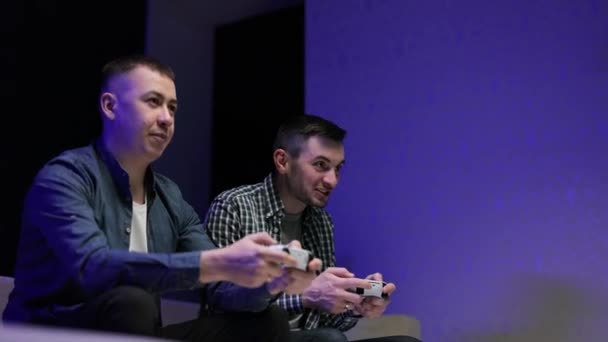 Jóvenes amigos masculinos jugando usando el joystick en casa. Caucásico hombres viendo tv a jugar videojuego juntos — Vídeo de stock