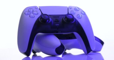 NEW YORK - 3 Mart 2021: Sony Playstation 5 denetleyici. Kamera, mavi ışıkta TV oyun kutusundaki beyaz kumanda etrafında dönüyor. İki beyaz oyun denetleyicisi Sony Playstation 5.