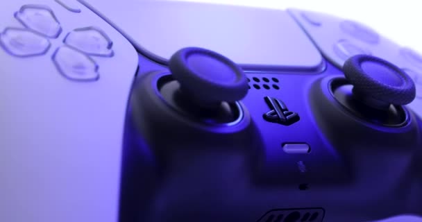 NEW YORK - 3 березня 2021: контролер Sony Playstation 5. Закрийте частини джойстика з нової консолі Sony PlayStation 5. Камера обертається навколо білого контролера з телевізійної коробки синього світла. — стокове відео