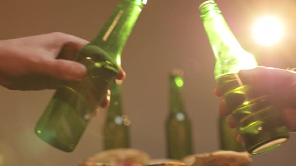 In Großaufnahme klappern Männer in einer Bar an Bierflaschen, abends entspannen sie sich. Freunde klirren mit Bierflaschen. Festbier jubelt Konzept zu. — Stockvideo