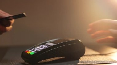 Faturayı ödemek için banka kartını araklarken kredi kartı terminali ile ödeme yapan adamın ellerini kapat. Adamın eli kredi kartı şifresine giriyor ve ödemeyi terminalden yapıyor.