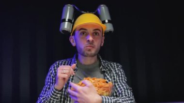 Beyaz adam evinde dinleniyor ve TV 'de TV programları ya da spor haberleri izliyor. Kafasında bira kaskı olan bir adam kanepede otururken cips yiyor, akşamları evde televizyon seyrediyor.