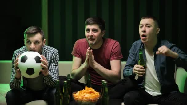 Trzy przystojny szczęśliwy biały przyjazny mężczyźni jedząc przekąski chipsy i rozweselić się na mecz piłki nożnej w telewizji siedząc na kanapie. mężczyzna przyjaciele oglądanie sport kanał zebrane razem. — Wideo stockowe