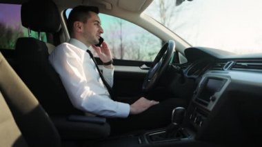 Yakışıklı şoför telefonda konuşuyor, akıllı telefon kullanarak sohbet ediyor. Genç bir iş adamı arabada cep telefonuyla konuşuyor. Yaşam tarzı, yol, araba konsepti.