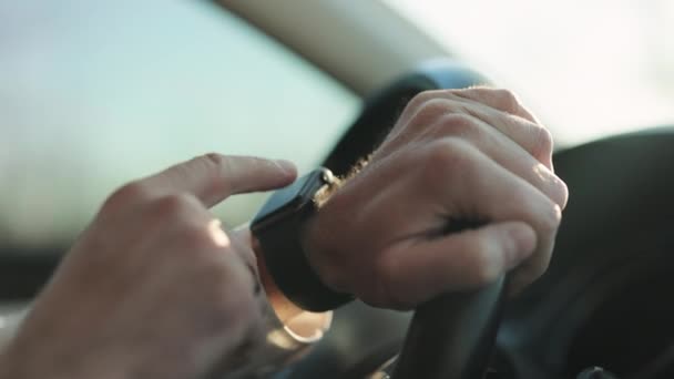Чоловік за допомогою програми розумного годинника перевіряє час сповіщення на зап'ясті рука водіння автомобіля розмита дорога носиться наручний годинник розумний годинник зайнятий торкаючись екрану, що стикається швидко — стокове відео