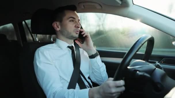 Όμορφος νεαρός οδηγός ιππασίας αυτοκίνητο και μιλώντας στο τηλέφωνο, έχοντας συνομιλία χρησιμοποιώντας το smartphone, μιλώντας κατά την οδήγηση. Τρόπος ζωής, δρόμος, αυτοκίνητο έννοια — Αρχείο Βίντεο