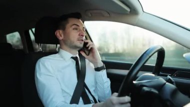 Erkek sürücü modern 3G 4G telefon kullanıyor. Yakışıklı, konsantre olmuş, araba kullanan ve akıllı telefonu kullanan bir adam. Rahat bir nakliye aracı. Çevrimiçi çalışan yetişkin bir serbest yazar. İş görüşmesi