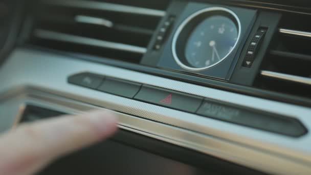 Primer plano de la mano caucásica masculina presionando el botón de luz de emergencia en el salpicadero del coche. Activación de las luces de peligro de un vehículo pulsando el botón del tablero. Pare al borde de la carretera, accidente de coche — Vídeos de Stock