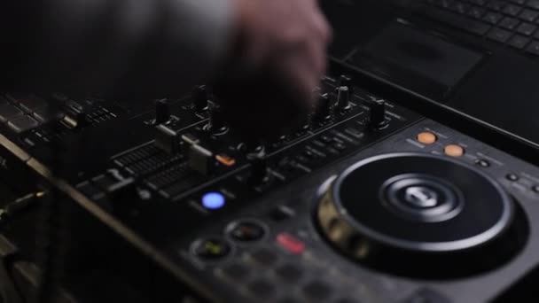 Mixer controller composing new mix on vinyl plate. DJ sound control console for mixing dance music in disco club. Hands touching buttons sliders, playing electronic music on mixing deck — Stock Video