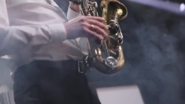 Konserde bandosu olan saksafoncu müzisyen. Müzik grubu şarkı söylüyor, sahne performansları sergiliyor. Caz grubunda solo çalan saksafoncu, hafif sahnede şarkı söylüyor.