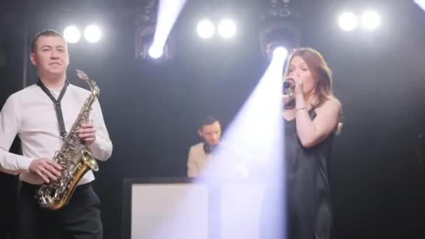 Gruppo musicale di cantante cantante donna, sassofonista sassofono, dj man che suona la canzone esibendosi sul palco musicista concerto con luci e ballando insieme. Festa, concerto di spettacolo del festival musicale — Video Stock