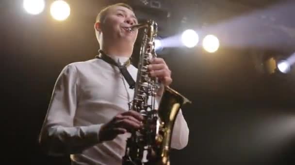 Cool saxophonist performing an amazing solo. Musician doing a concert. Sax musician player with band at concert. Musical band group playing song, performing on concert musician stage with lights — Stock Video