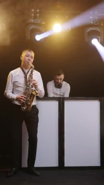 Gece kulübünde DJ Müzik Çalıyor. Saksafoncu adam gece kulübünde saksafon çalıyor, dans ediyor, DJ 'le konser sahnesinde şarkı söylüyor. Parti, müzik festivali konsepti.