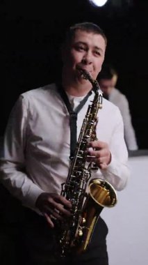 Saksafoncu Play 'in Altın Saksafon' daki dikey ekran videosu. Havalı saksafoncu sahnede solo performans sergiliyor. Grupta müzisyen çalıyor. Canlı performans. Caz müziği