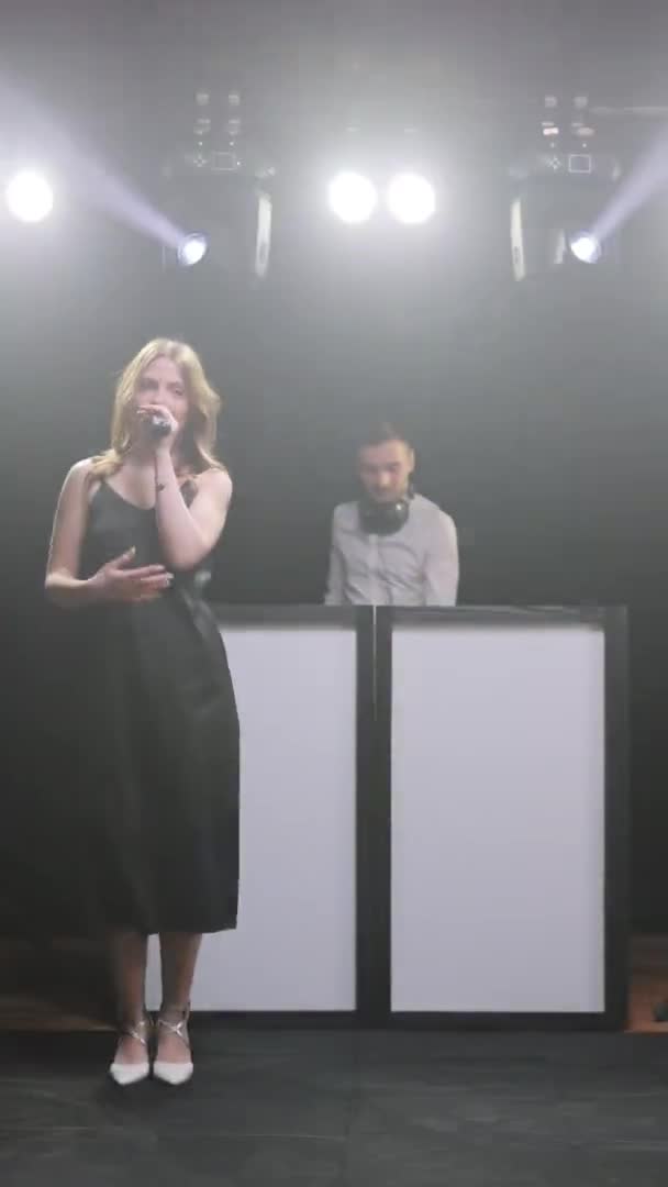 Вертикальный экран Видео певицы вокалистки и диджея, играющего песню на концертной сцене музыканта со светом. Концерт на музыкальном фестивале — стоковое видео
