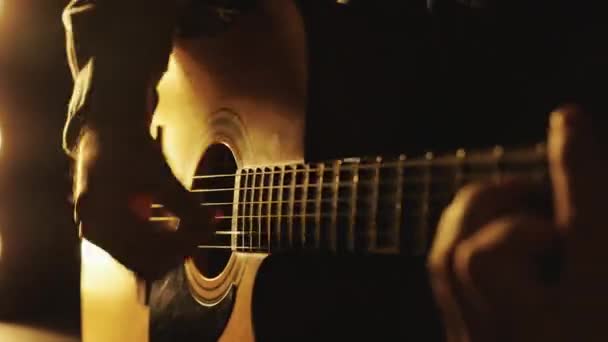 O guitarrista toca numa guitarra clássica. Mão de homem tocando guitarra no quarto escuro. Pessoa irreconhecível ensaiando com guitarra acústica em estúdio de gravação — Vídeo de Stock