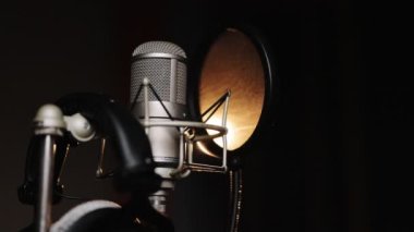 Stüdyo kaydı, kayıt stüdyosunda profesyonel mikrofon, duvarın yanında akustik nemlendirici köpüklü mikrofon. Sahnede siyah arkaplana karşı ışıklandırmalı bir mikrofon yakın plan.