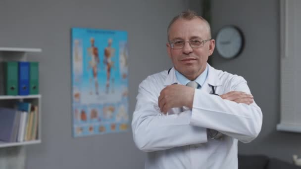Porträtt av den kaukasiska familjens läkare i glasögon finns på hälsokliniken. Framgångsrik läkare i White Lab Coat Titta på kameran och leenden på sjukhusets kontor — Stockvideo