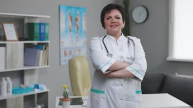 Kendinden emin yaşlı yetişkin kadın profesyonel doktor, yaşlı doktor beyaz önlük giyiyor steteskop takıyor hastane ofisindeki kameraya bakıyor. Sağlık ve Tıp Konsepti